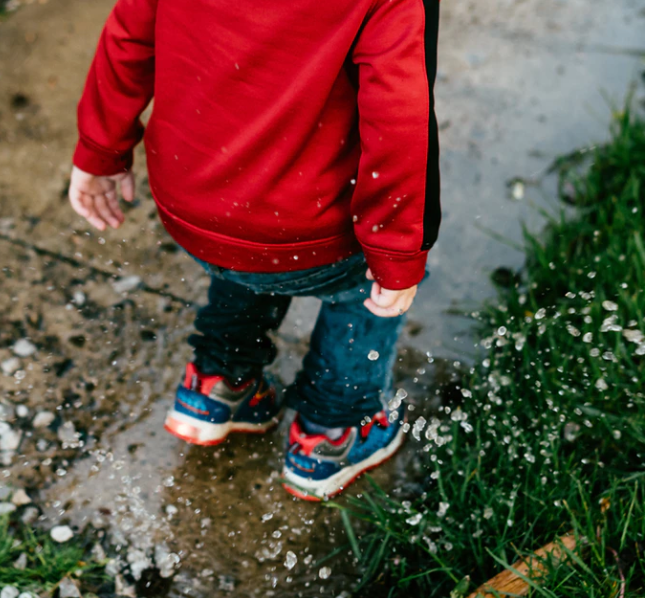 school buy jumping in a puddle