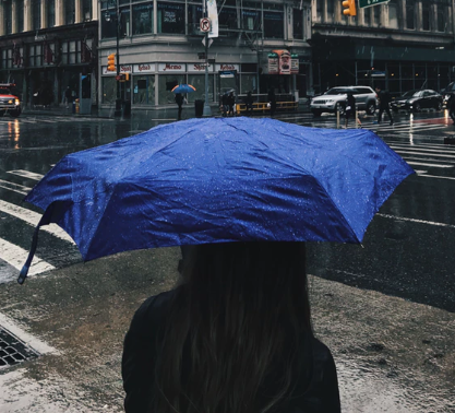 a woman on a street holding a navy umbrella