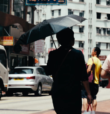 a woman carrying a black umbrella in a city