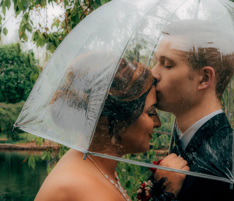 a bride nad groom under a clear wedding umbrella