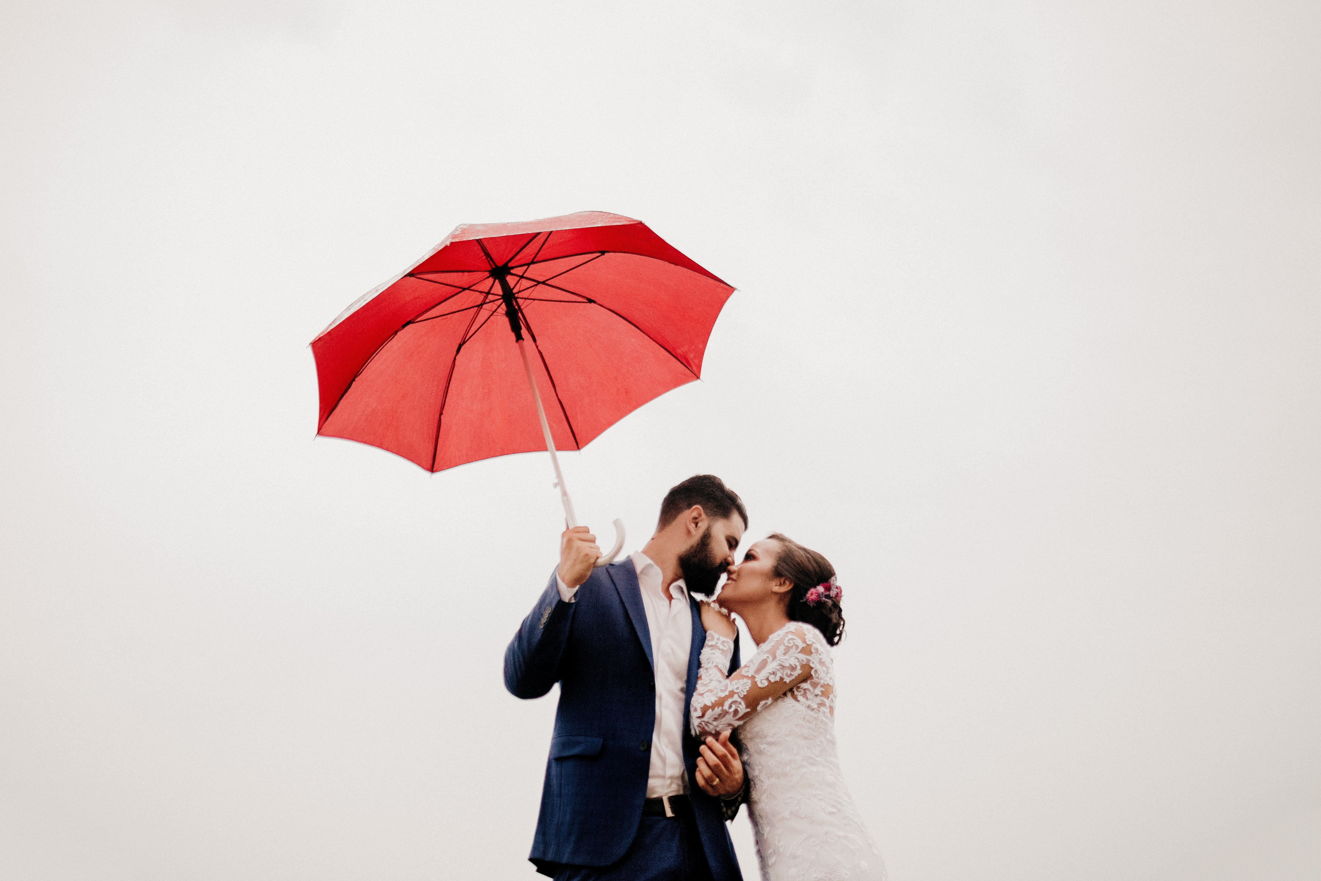 bride and groom under a red umbrella